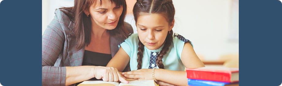 young girl getting reading instruction from teacher